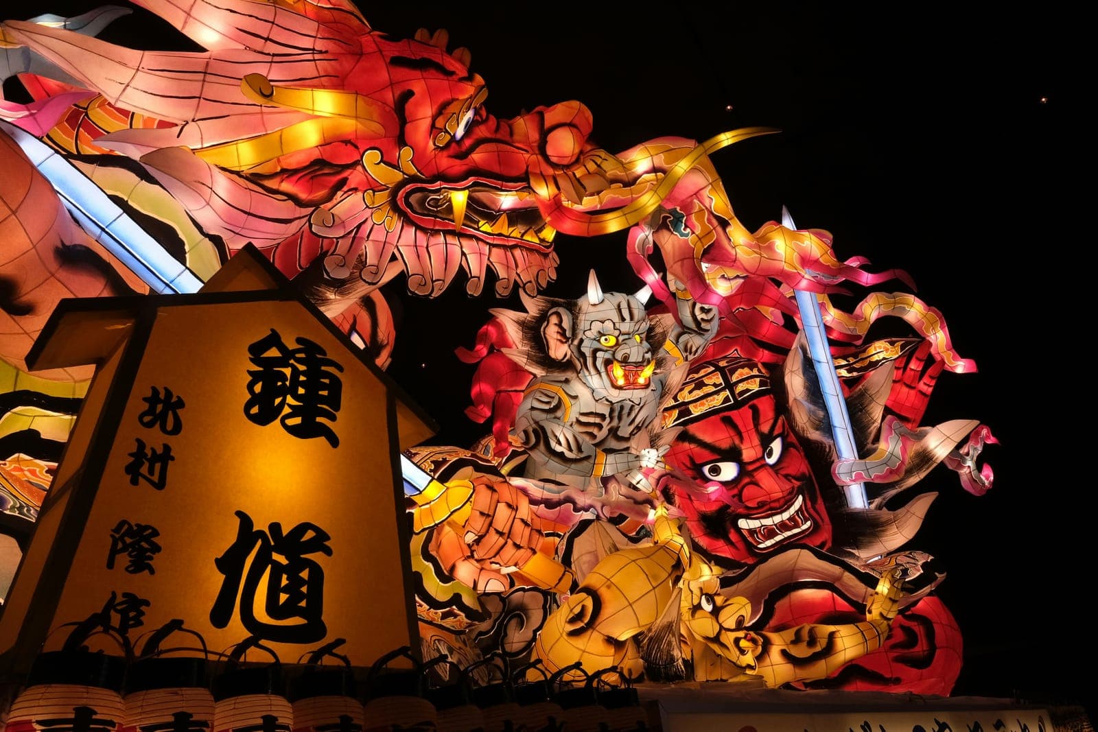 Brightly lit Nebuta festival floats glowing against the night sky in Aomori