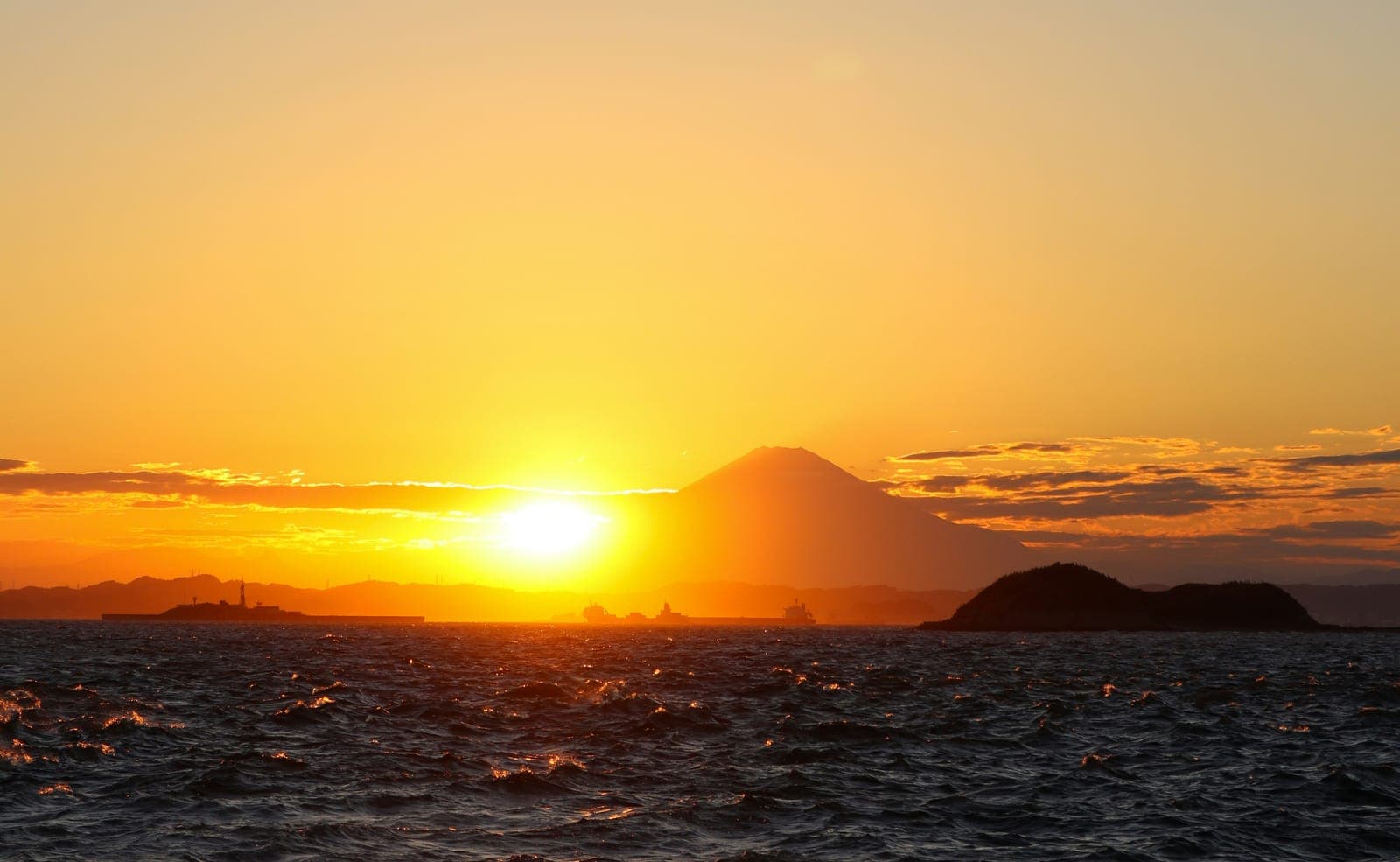 千葉の海岸から望む、水平線に富士山が浮かぶ夕日