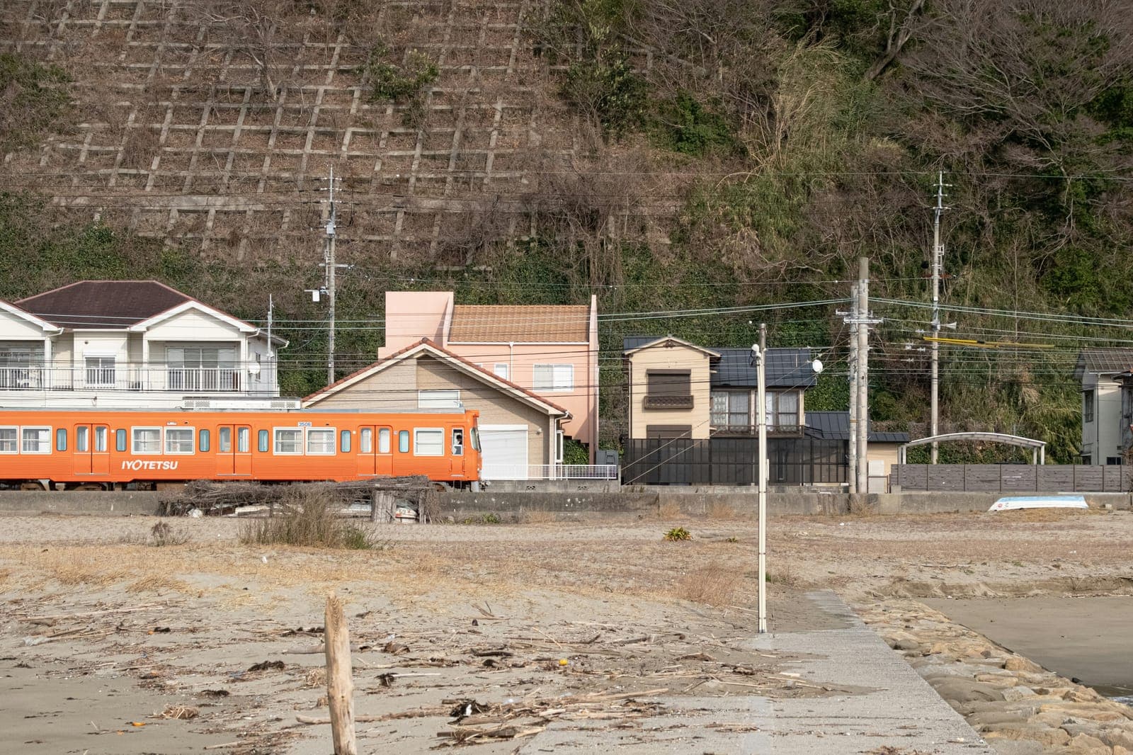 愛媛の海沿いを走るオレンジ色の伊予鉄道のローカル列車
