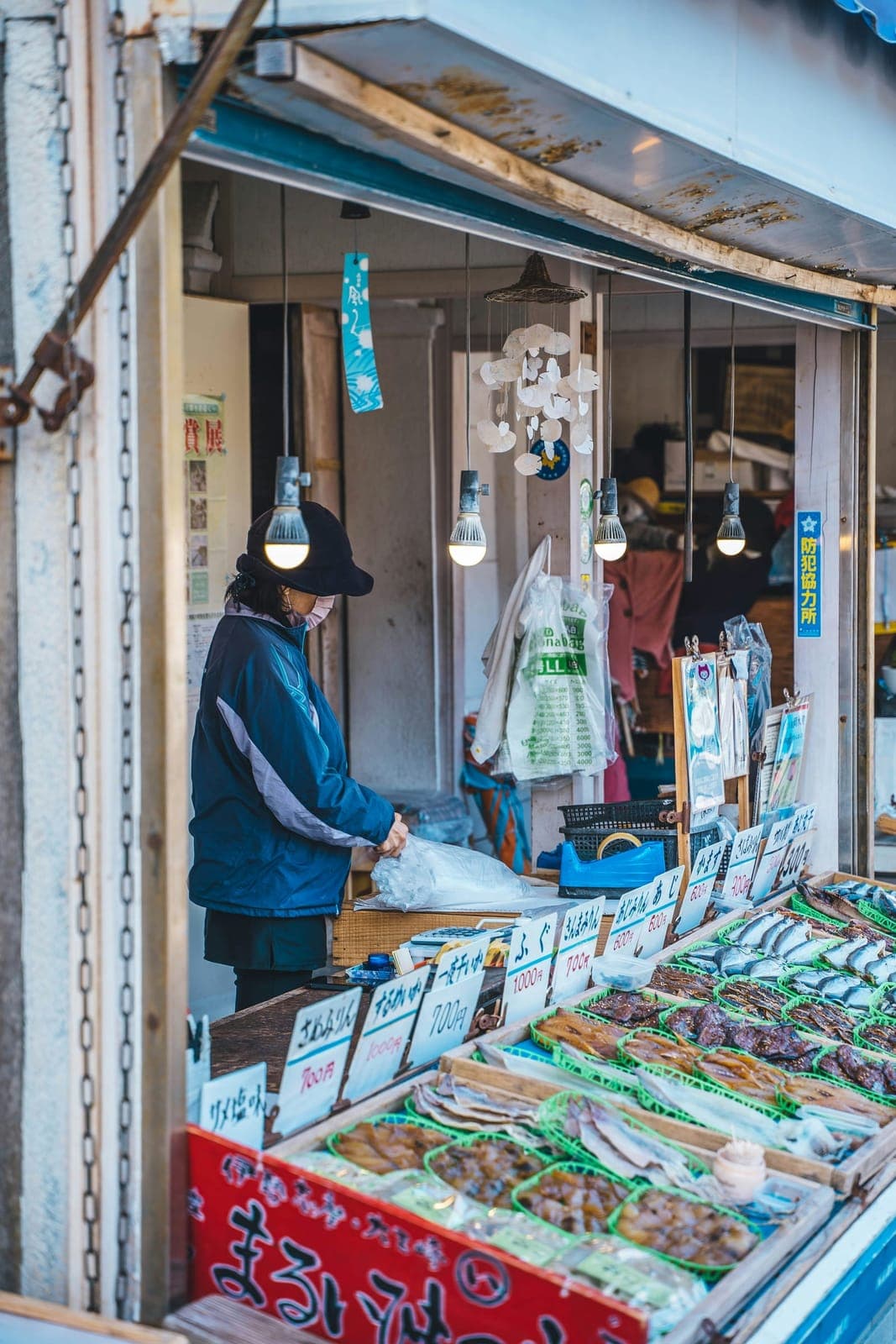 三重の海辺の市場で、干物を並べる店先に立つ店主